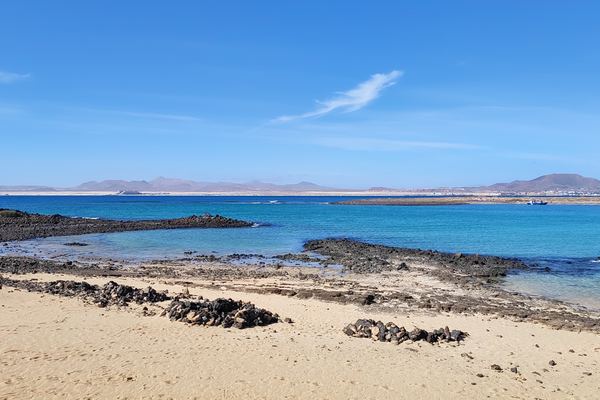 Aguas turquesas de la Playa de la Concha, con Fuerteventura al fondo